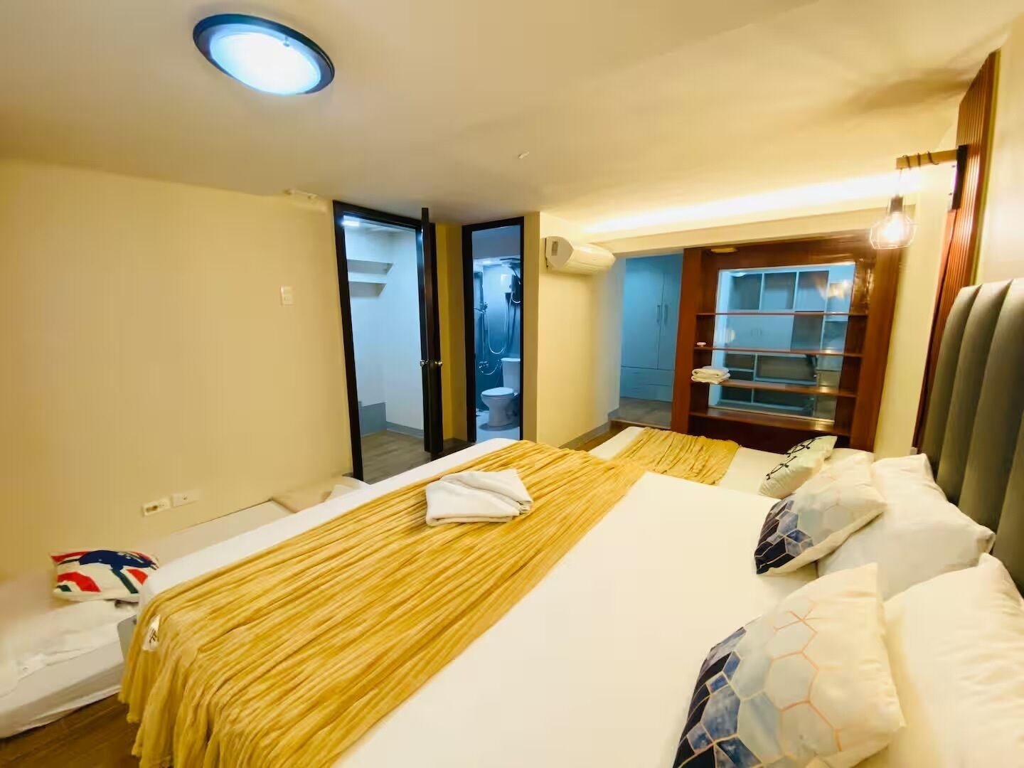 A hotel room with a bed, a mirror, a wardrobe, and a bathroom visible through an open door.