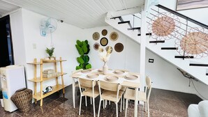 A dining area with a round table, chairs, a plant, and a staircase with a modern design. - Luxury Loft in Cebu City (Cebu City)