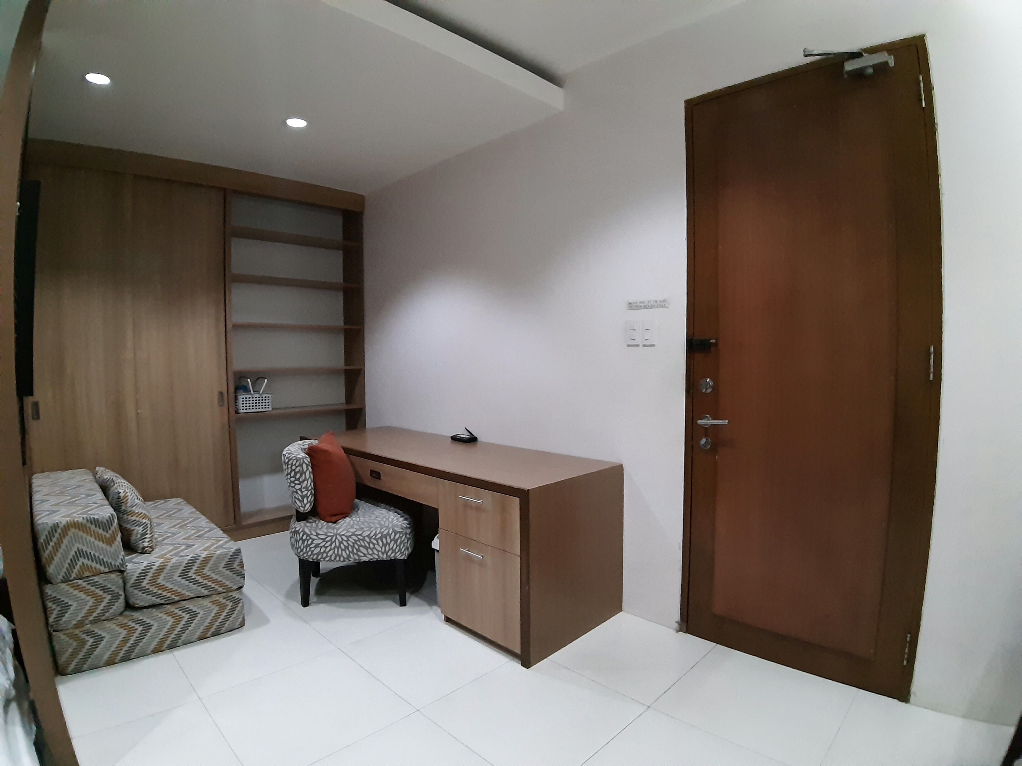 Een kamer met een houten bureau, een stoel, een bank en een garderobe.