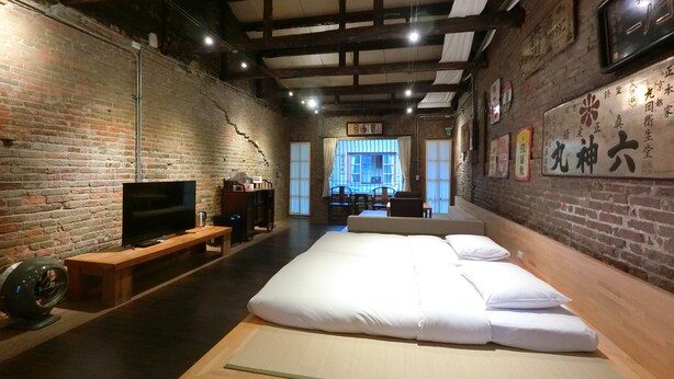 Una habitación con una cama grande, televisión y una pared de ladrillo.