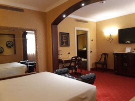Una habitación de hotel con cama, escritorio, silla, televisor y armario.