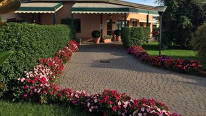 A motel with a sign reading "MOTEL" above the entrance, surrounded by well-maintained hedges and flower beds. - Hotel Motel Luna (Segrate)