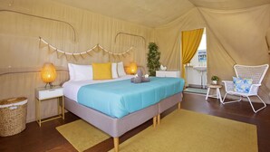 A bedroom with a bed, bedside lamps, a chair, a small table, and a plant. - The Eco Beachcamp Retreat (Eurong)