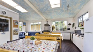 A compact kitchen with a dining area, a built-in oven, and a large window providing natural light. - The Eco Beachcamp Retreat (Eurong)