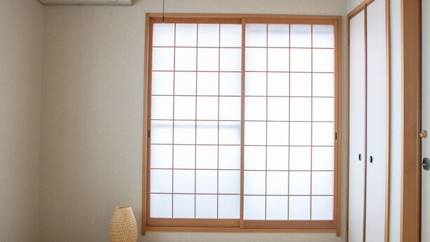 A traditional Japanese room with tatami flooring, a shoji screen door, a ceiling fan, and a small woven basket. - Guesthouse ILOHA (Kyoto)