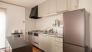 A modern kitchen with stainless steel appliances, including a refrigerator, microwave, and dishwasher. - Guesthouse ILOHA (Kyoto)