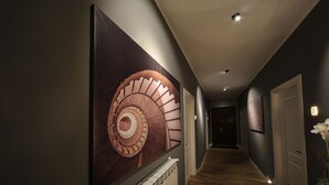 A hallway with a spiral staircase, a radiator, and a door at the end. - K Rooms (Rome)