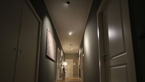 A narrow hallway with wooden flooring, white doors, and recessed lighting. - K Rooms (Rome)