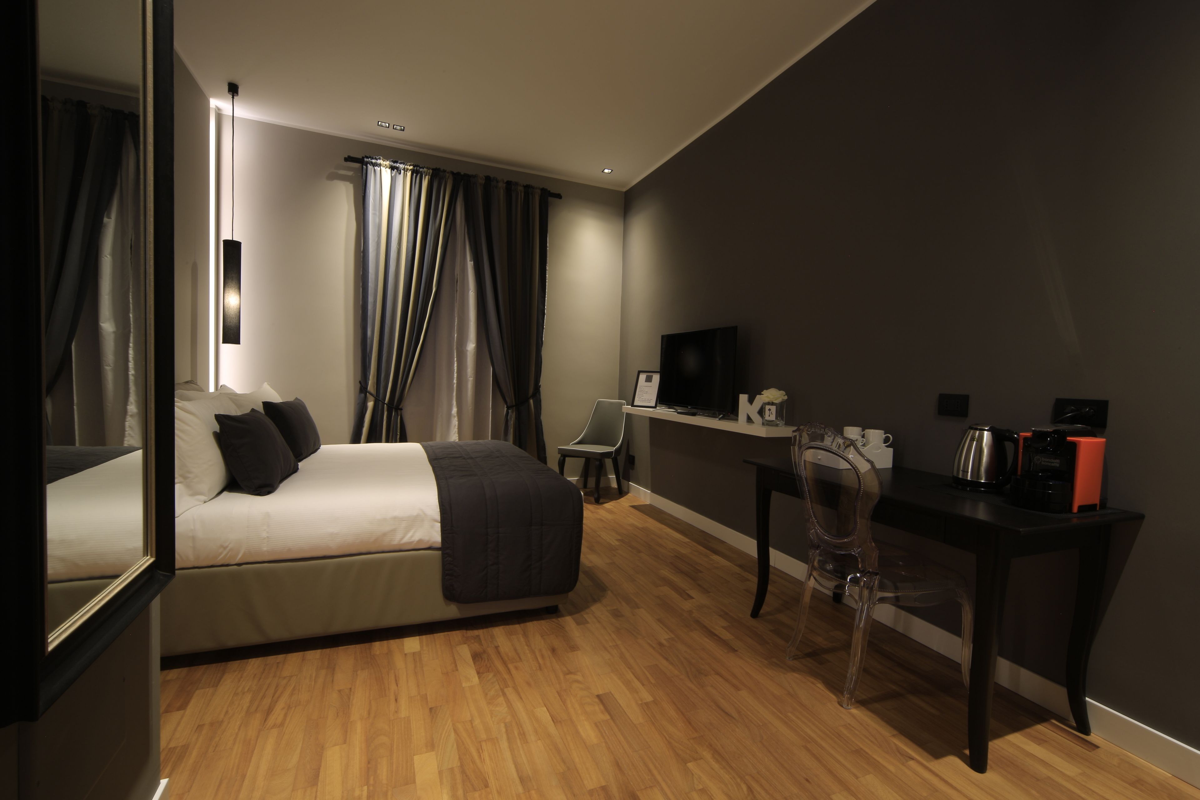 A modern hotel room with a bed, desk, chair, and a television.