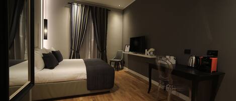 A modern hotel room with a bed, desk, chair, and a television.