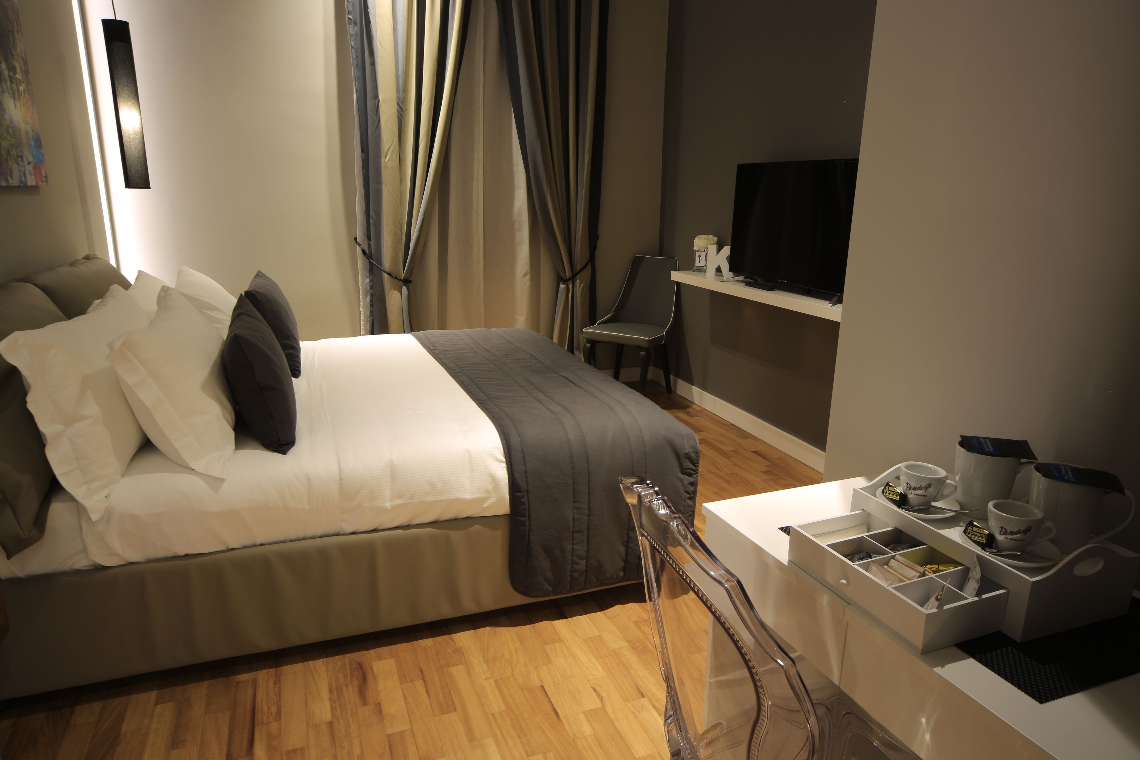 Ein ordentlich eingerichtetes Schlafzimmer mit Bett, Nachttisch und Fernseher auf einem Schrank.