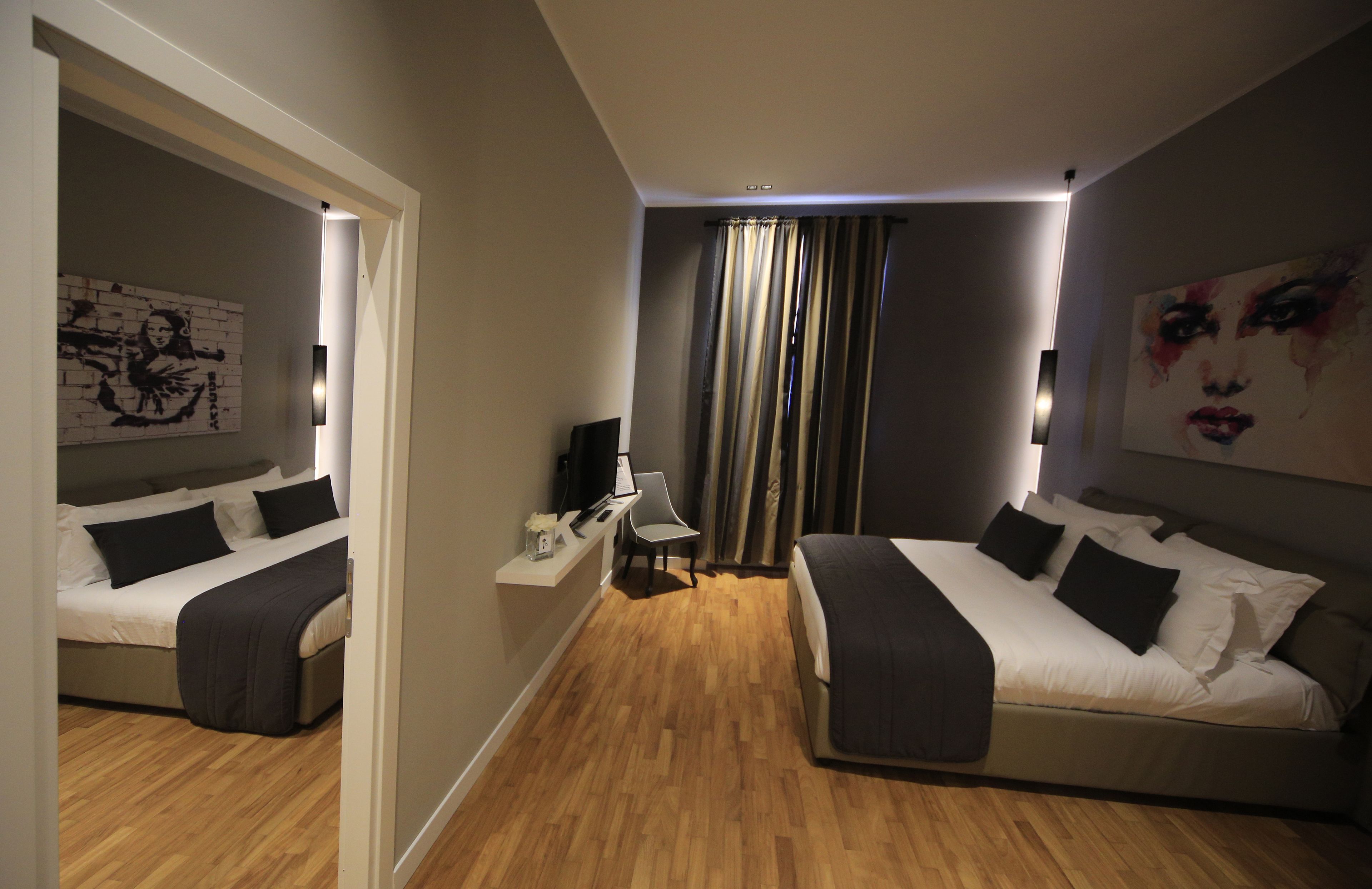 Una habitación de hotel moderna con dos camas, un escritorio, una silla y un amplio ventanal con cortinas.
