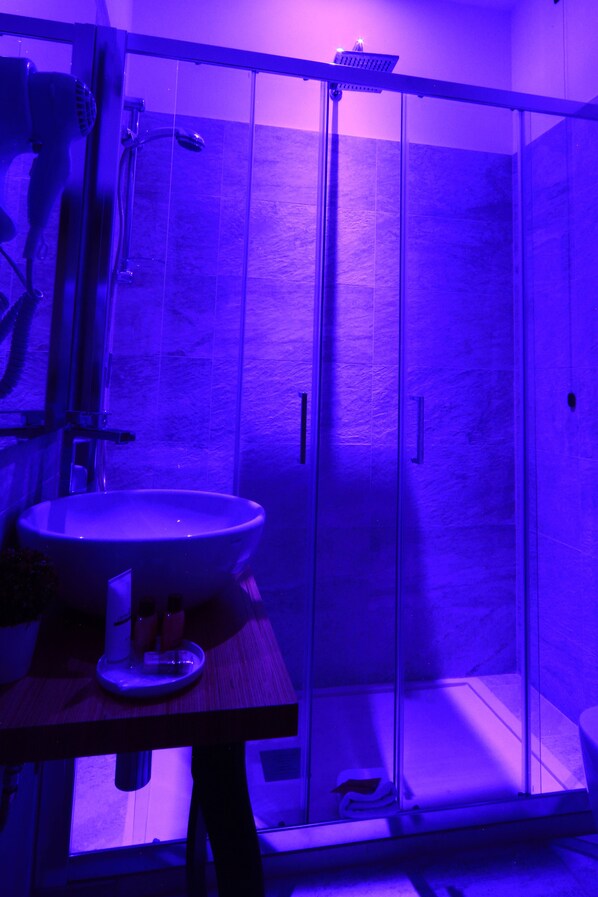 Un baño con cabina de ducha de vidrio, lavamanos y secador de pelo.