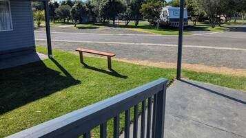 A grassy area with a bench, a paved road, and a parked RV.