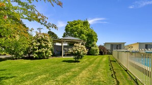 A well-maintained lawn with a gazebo, a swimming pool, and a fenced area. - Traralgon Holiday Village (Traralgon)