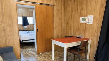 A room with a bed, a table with a chair, a sofa, and a wooden wall.