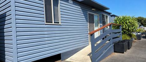 Una casa móvil azul con una escalera de madera y un porche amurallado.