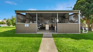 A small, single-story building with a covered patio area, a counter, and a sign indicating it is a day parking area. - Traralgon Holiday Village (Traralgon)