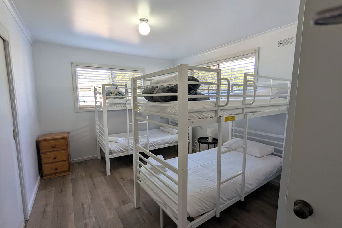 Una habitación con literas, un aparador de madera y una ventana con persianas.