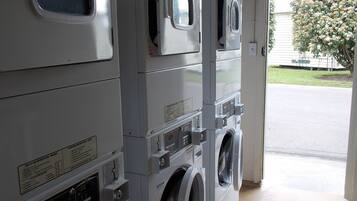 A row of stacked front-loading washing machines in a commercial setting.