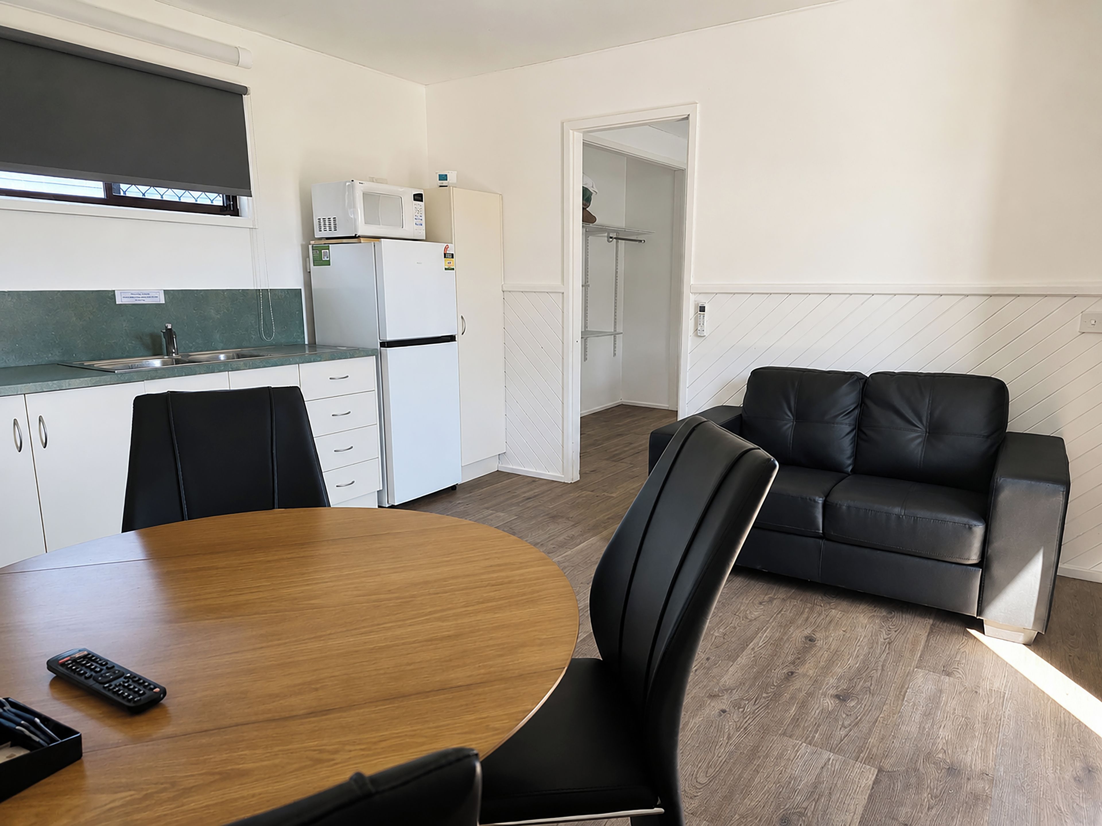 A modern kitchen with a dining table, chairs, and a remote control.