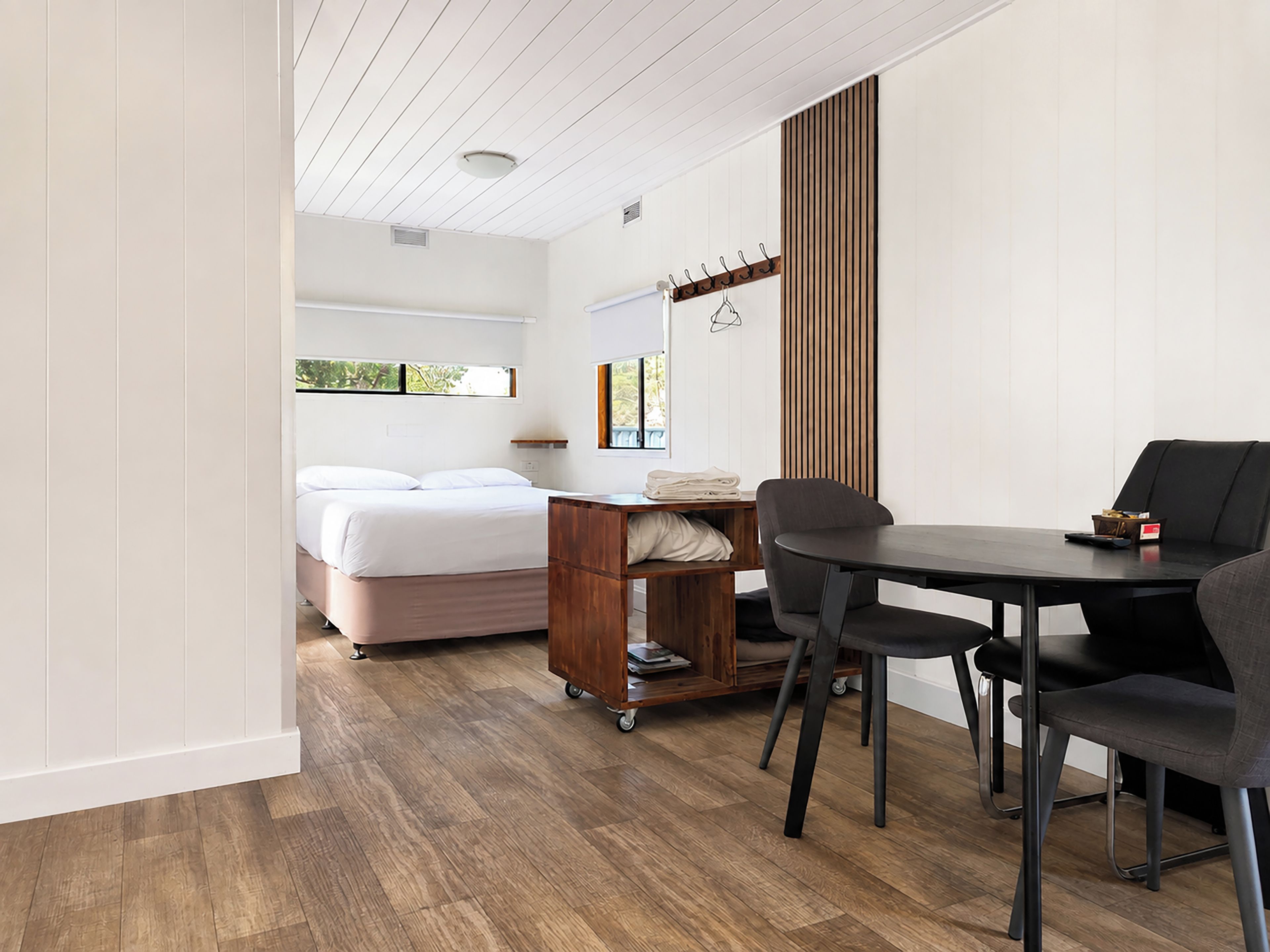 A bedroom with a bed, a bedside table, and a window.