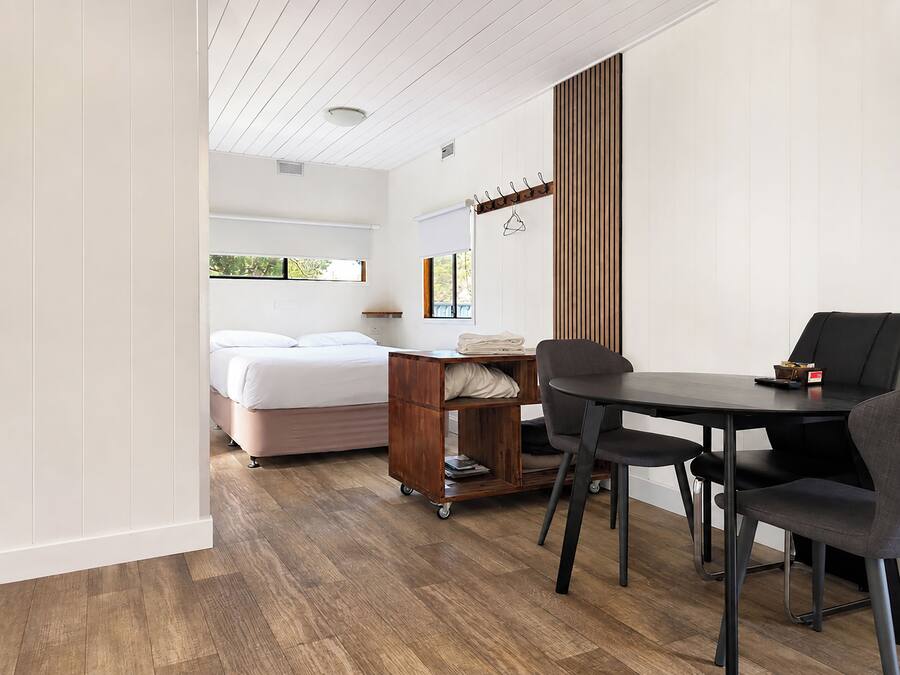 A bedroom with a bed, a bedside table, and a window.