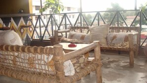 Un balcon agrémenté de meubles en osier, notamment un canapé et une table sur laquelle se trouve un objet rouge.