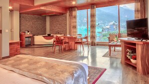 Une chambre d’hôtel moderne dotée d’un grand lit, d’une télévision, d’un coin repas et offrant une vue sur les montagnes.