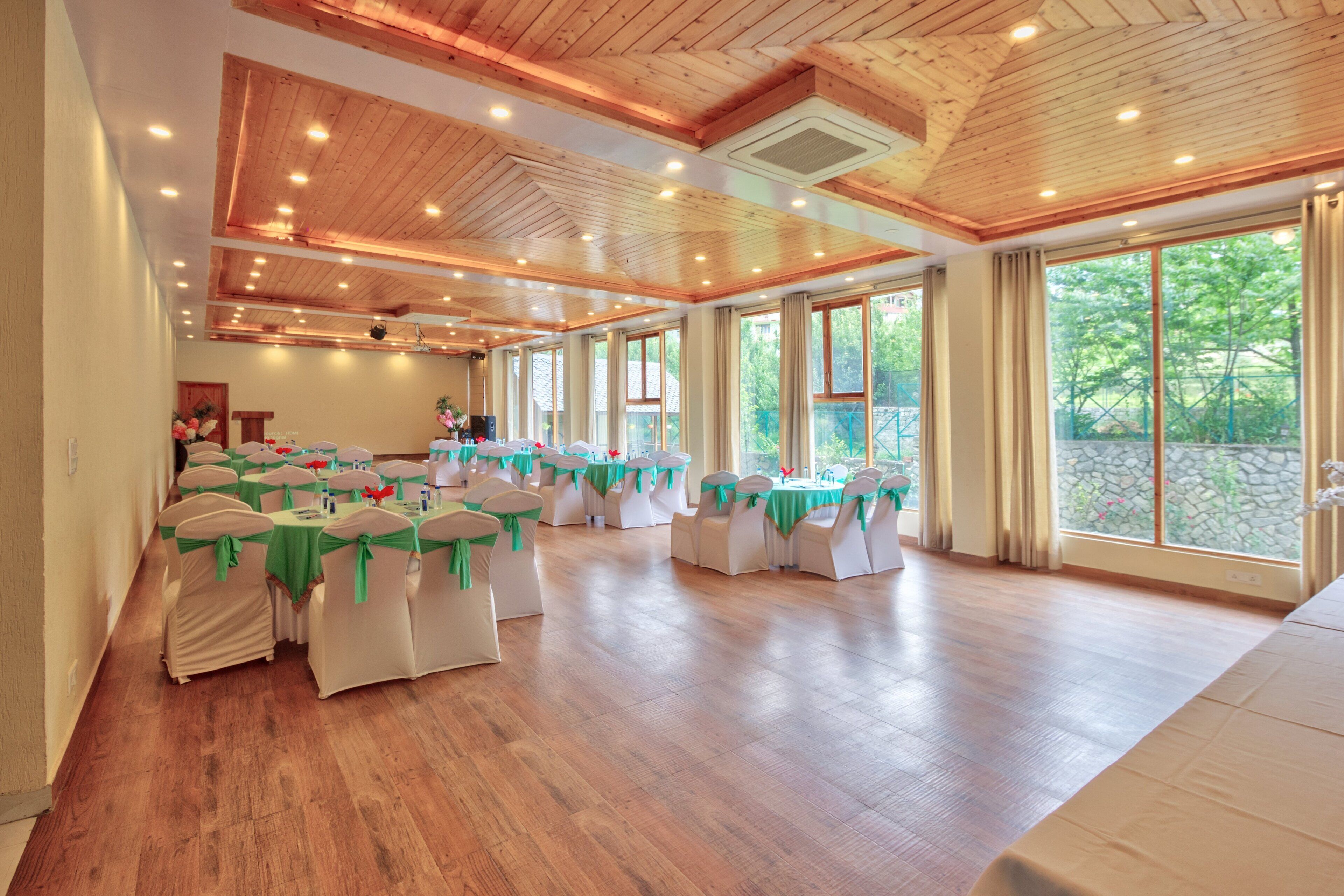 A spacious hall with wooden floors and ceiling, arranged with tables and chairs for events.