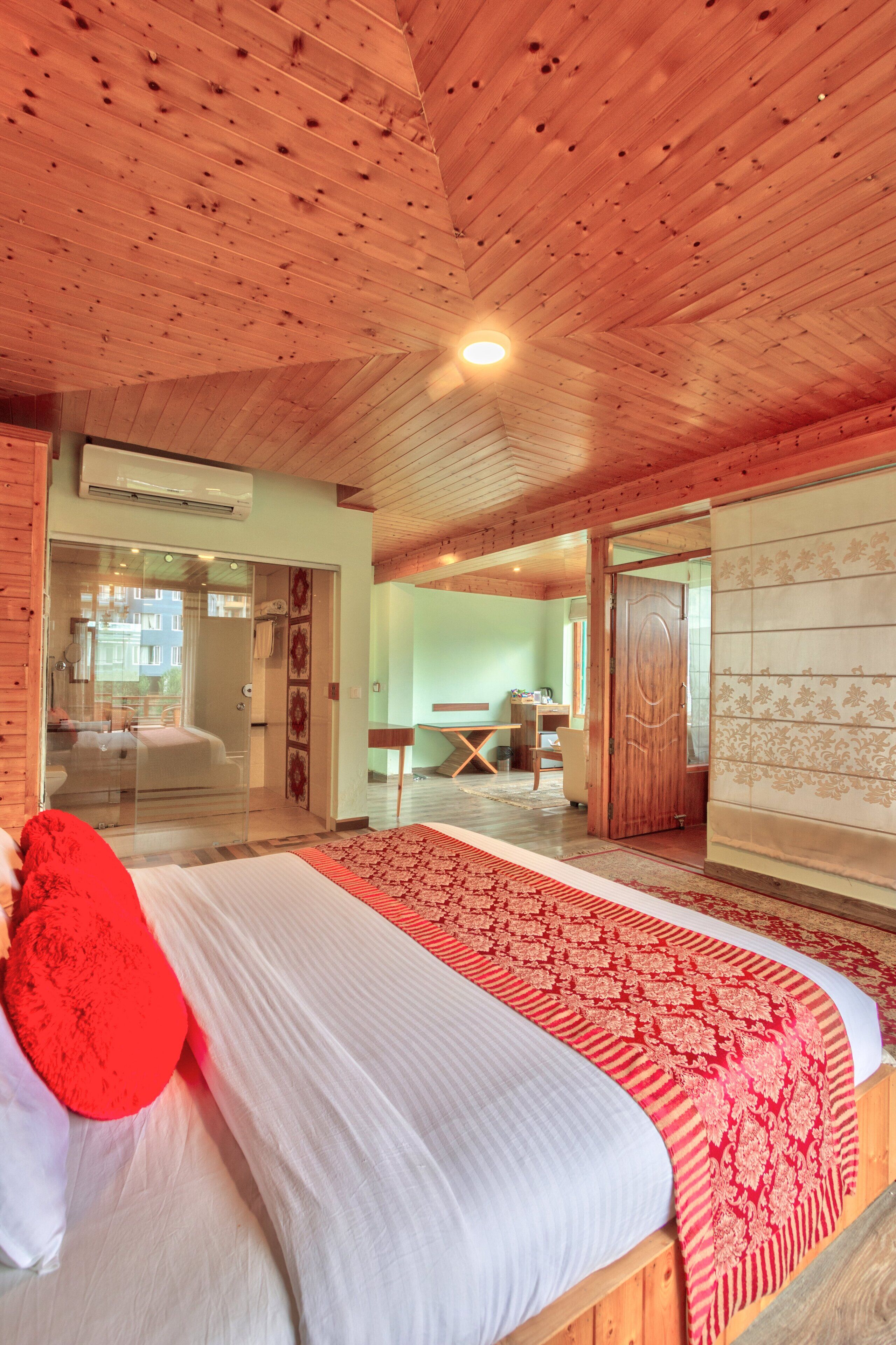 Ein Schlafzimmer mit einem großen Bett, einer Holzbalkendecke und einer Schiebetür zu einem Badezimmer.