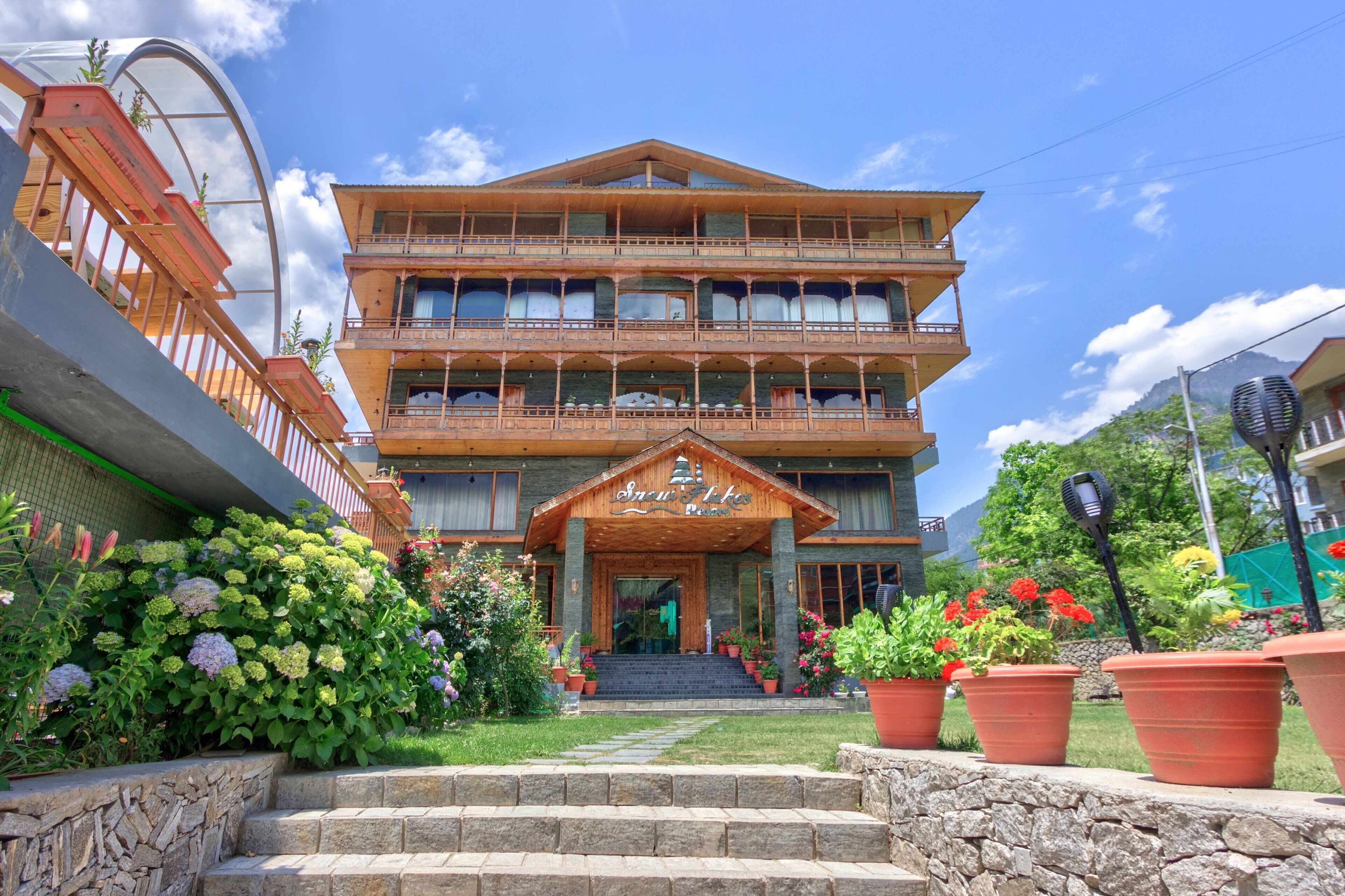A multi-story hotel with a wooden facade, balconies, and a stone staircase leading to the entrance.