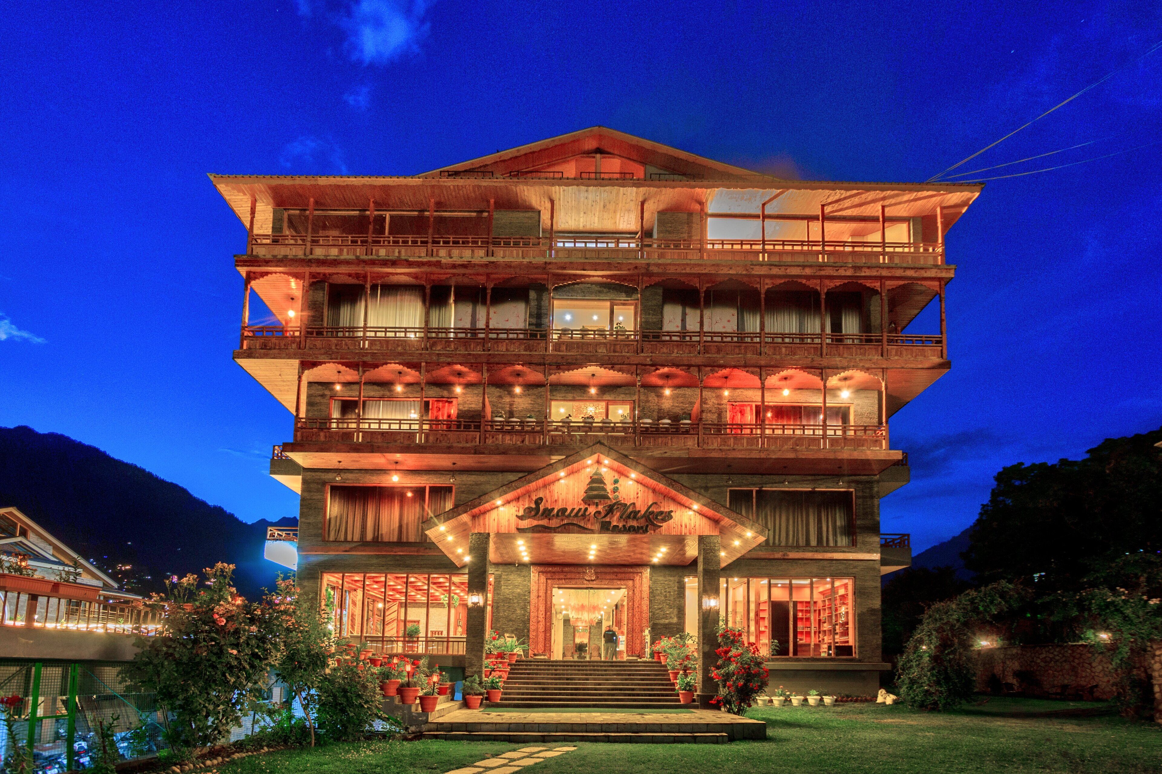 A multi-story hotel with a prominent entrance, balconies, and a well-lit facade.