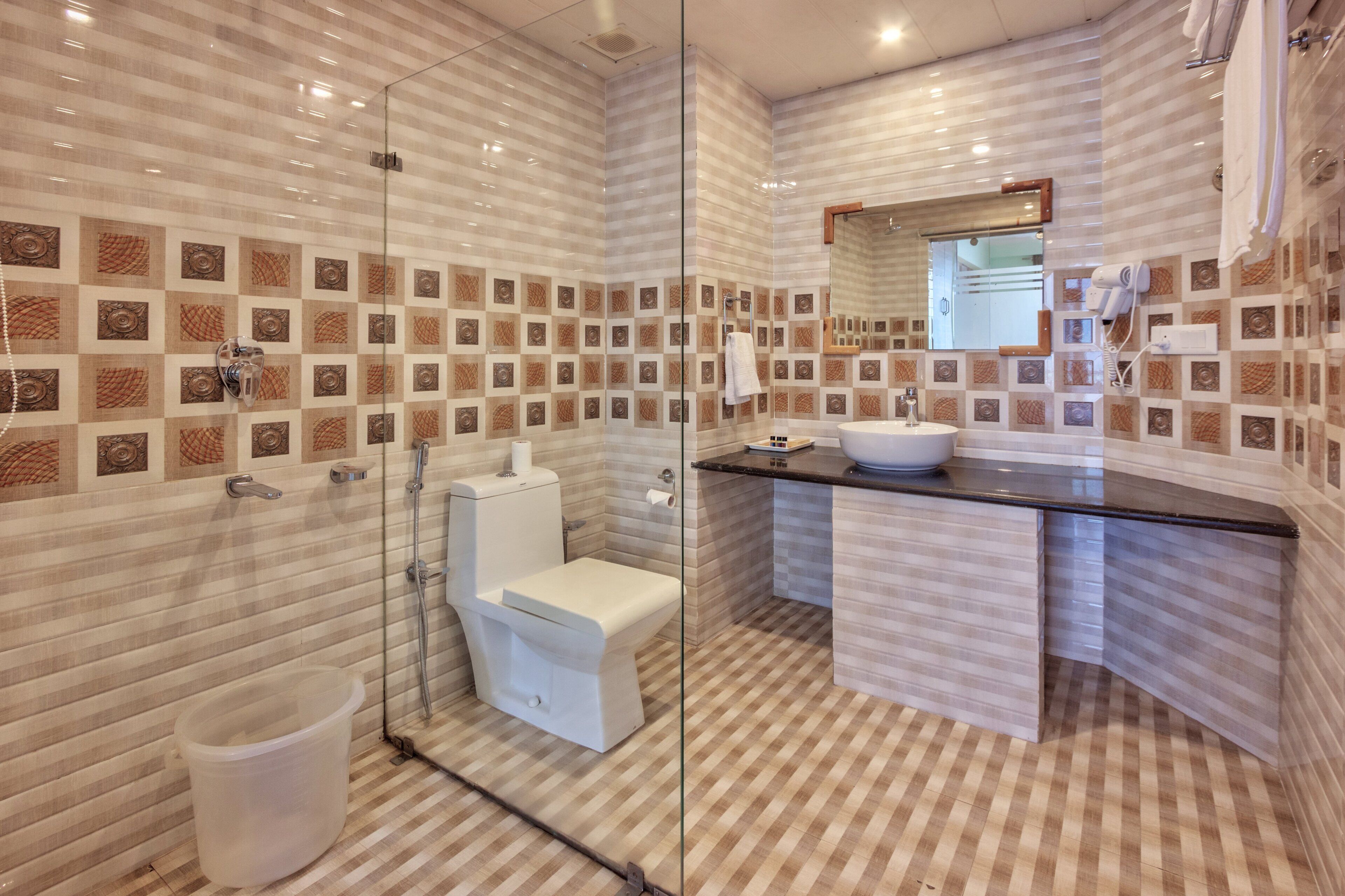A modern bathroom with a glass-enclosed shower, a white toilet, and a sink with a black countertop.