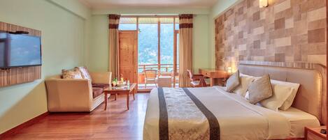 A hotel room with a large bed, a TV, a balcony with a view, and a wooden floor.