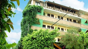Um edifício com várias andares, varandas e fachada verdejante.