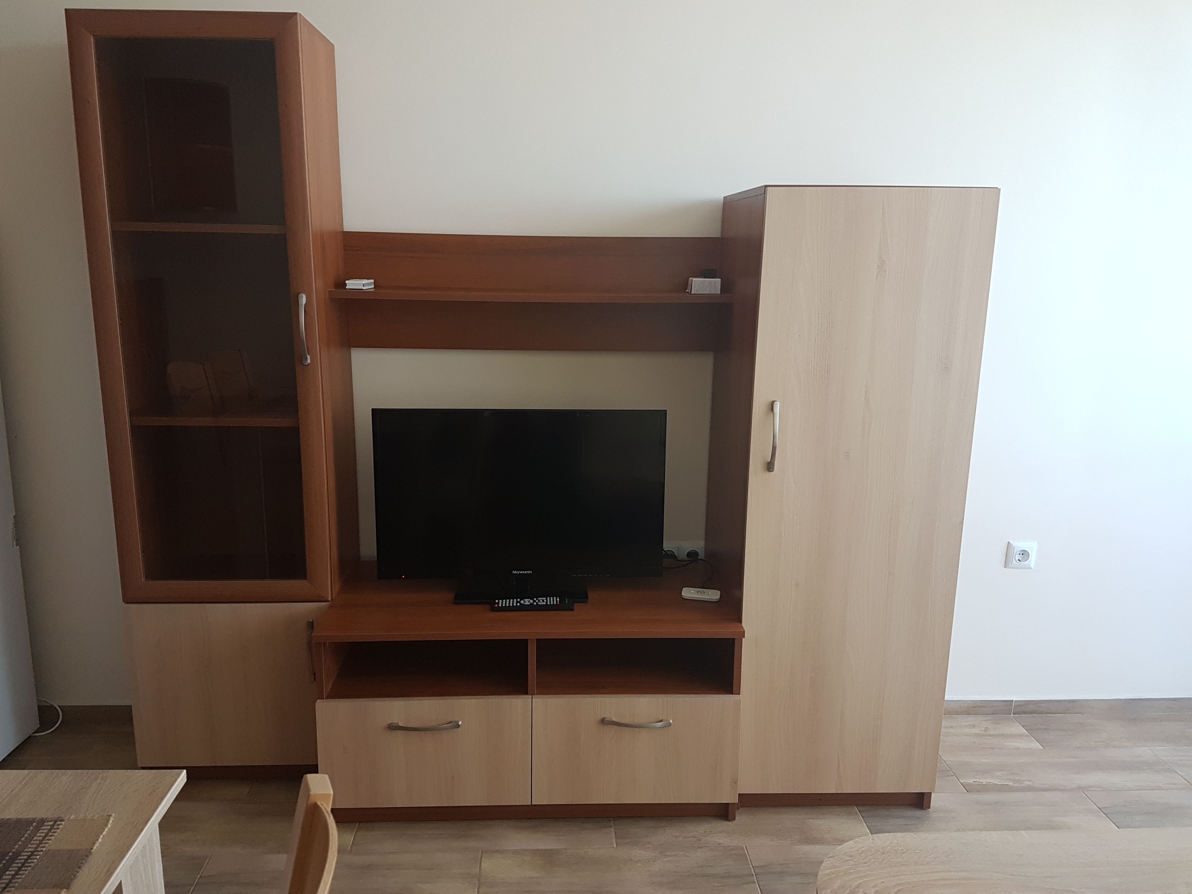 Ein Holz-Multifunktionsmöbel mit einem Flachbildfernseher, zwei Schubladen und einem Schrank.