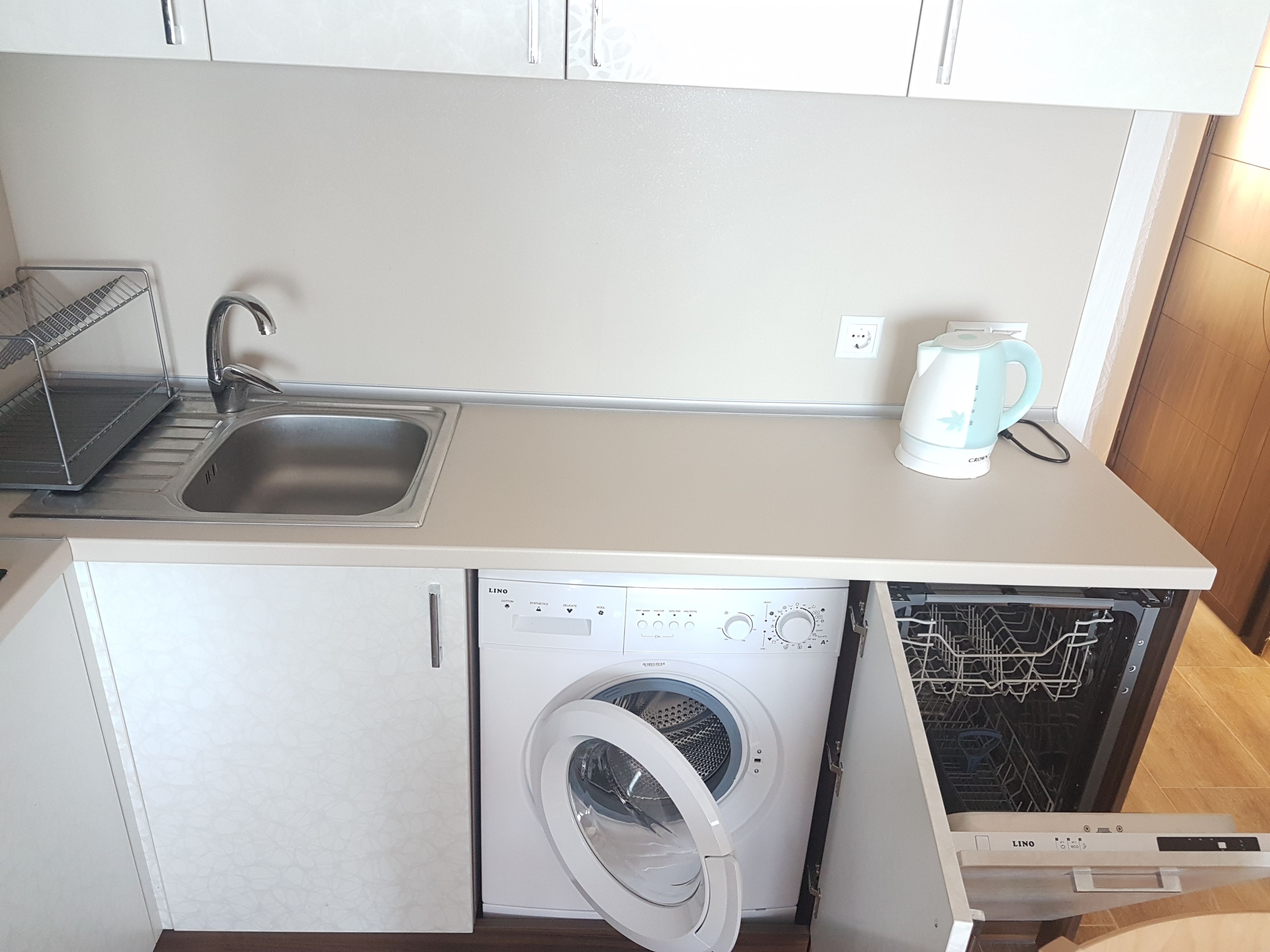 A compact kitchen with a sink, a coffee maker, and a built-in washing machine.