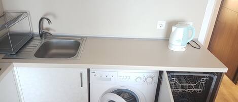 A compact kitchen with a sink, a coffee maker, and a built-in washing machine.