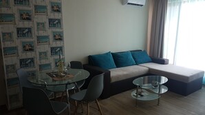 A modern living room with a glass dining table, a sofa, and a coffee table. - Apart Hotel Iglika (Pomorie)