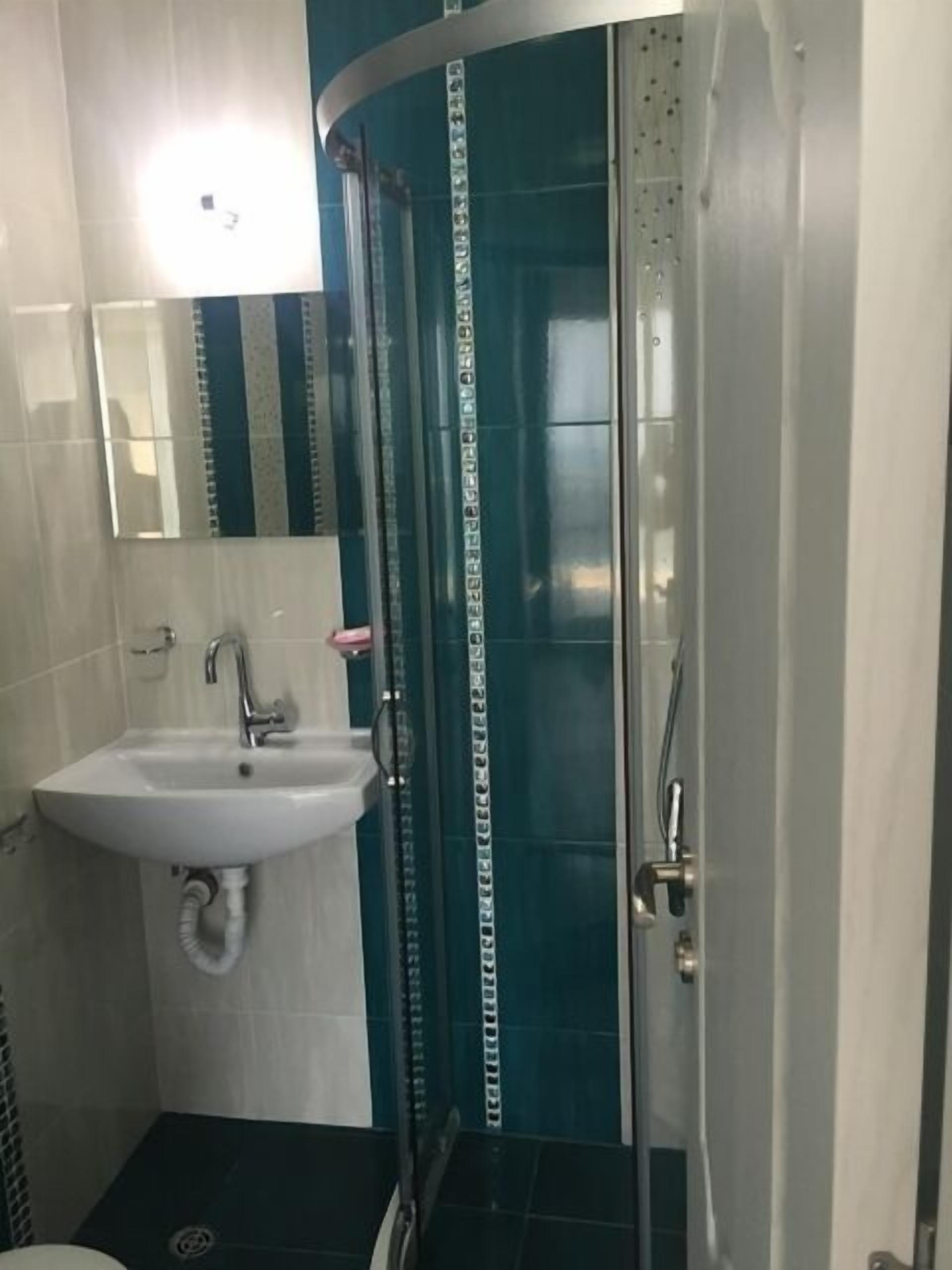 Ein Badezimmer mit einem weißen Waschbecken, einem Spiegel und einer Dusche mit Glastür.