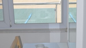 A room with a view of the beach, a table with cups and saucers, and a chair. - Yasmin Hotel (Ayvalik)