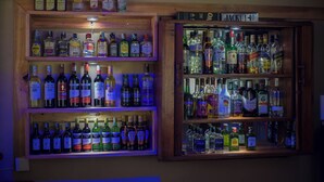 Eine Bar mit mehreren Regalen voller Spirituosenflaschen, darunter Marken wie Jack Daniel's und Bacardi.