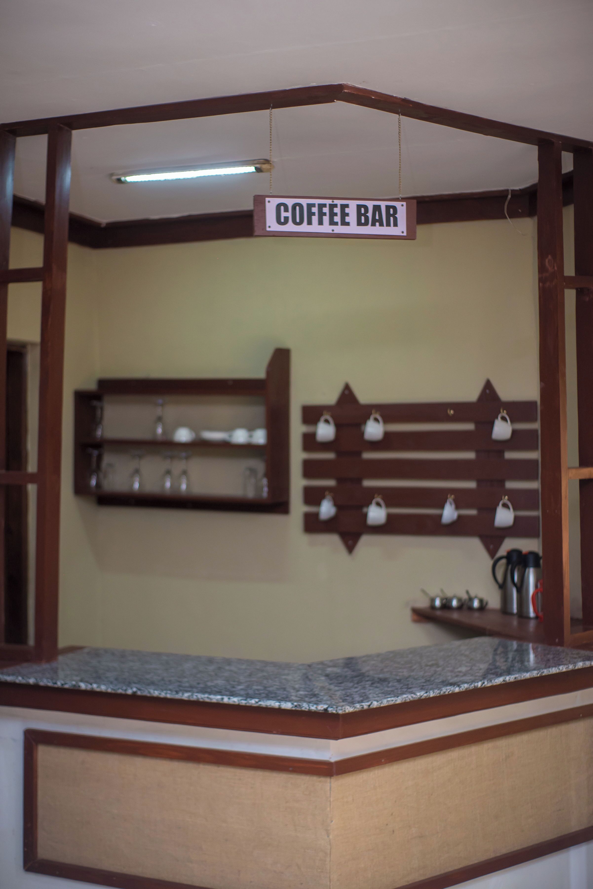 A coffee bar with a sign, shelves with cups, and a countertop.