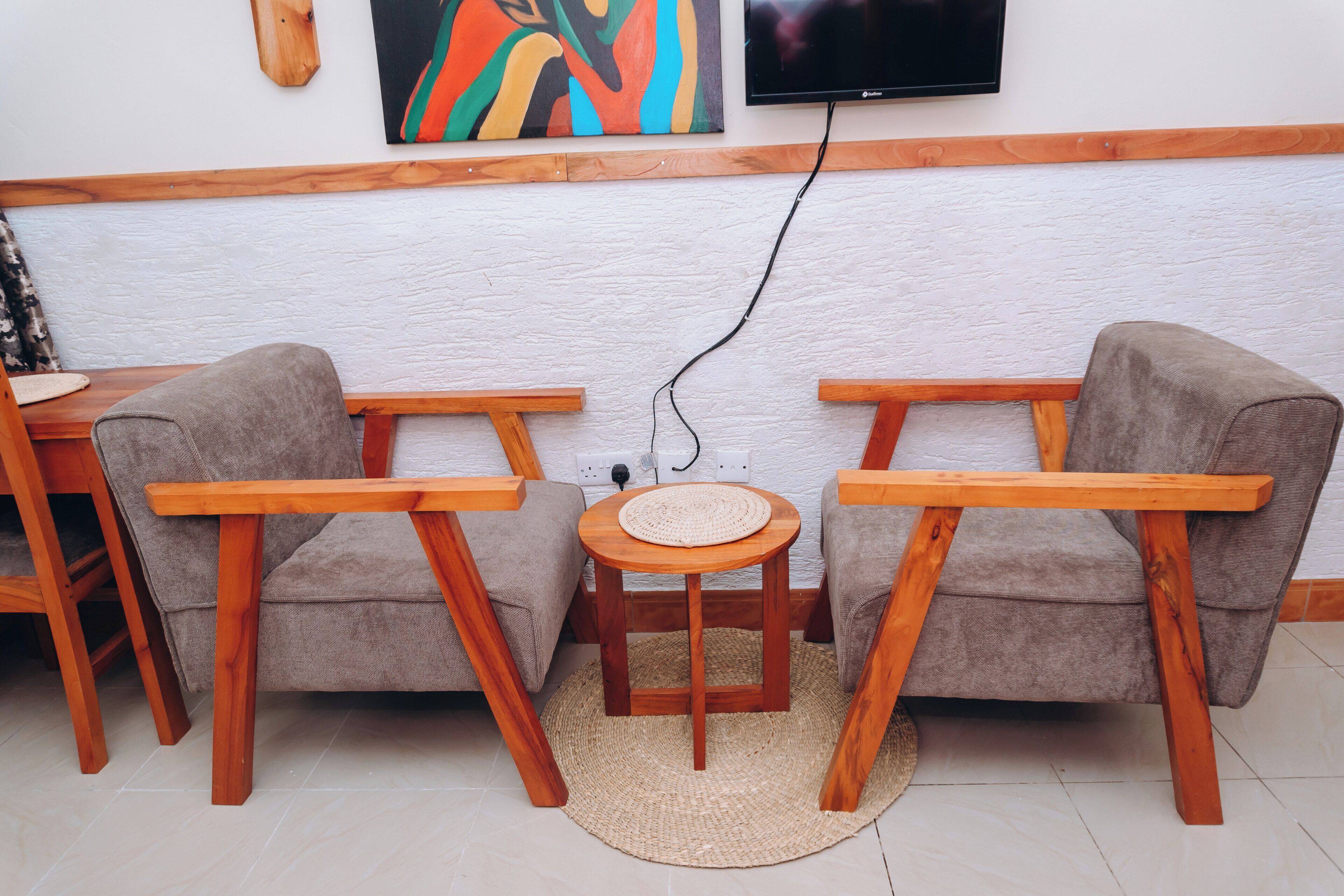 A room with two sofas, a small round table, and a TV mounted on the wall.