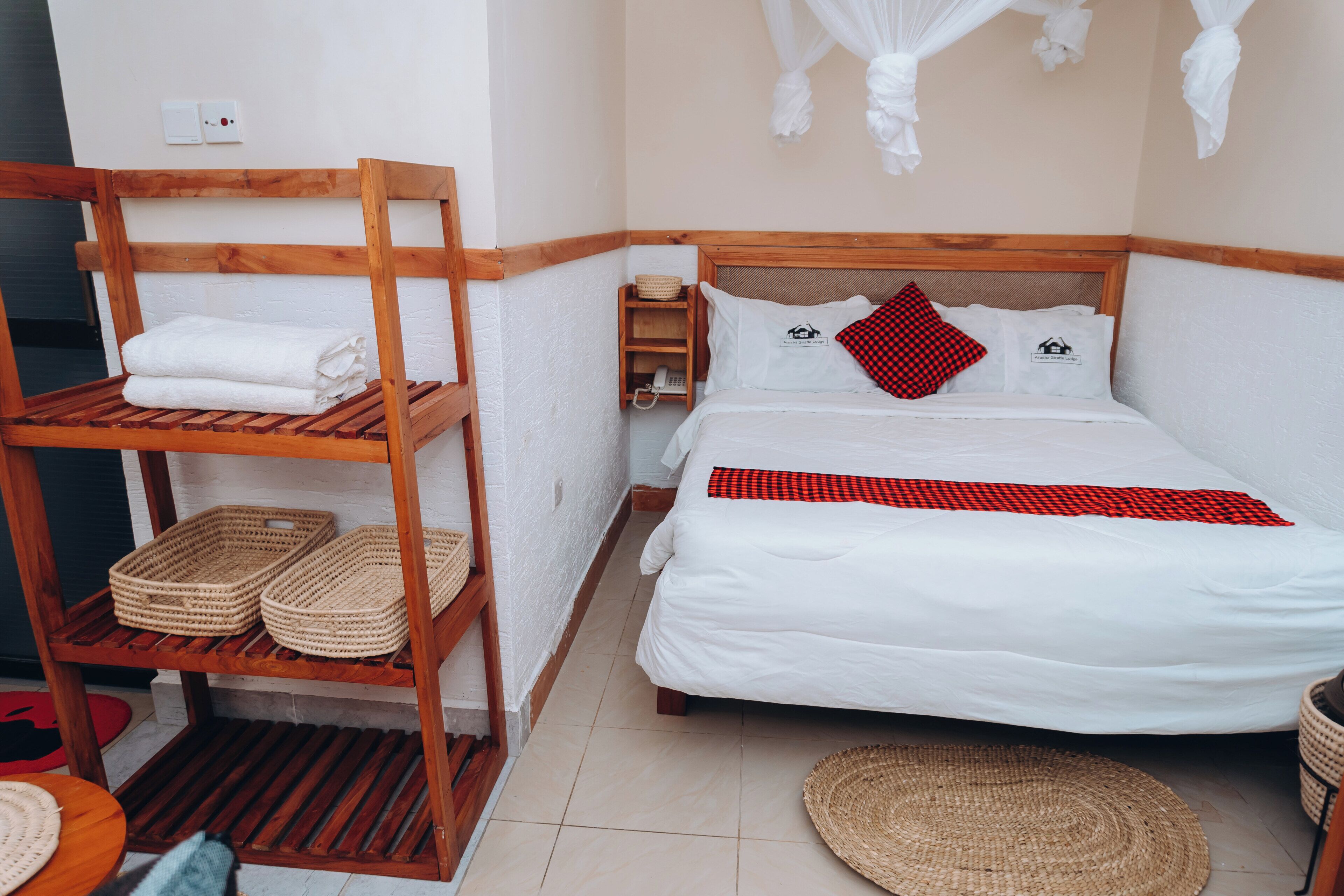 A bedroom with a wooden bunk bed, a single bed with a red and black checkered blanket, and a woven basket on the shelf.