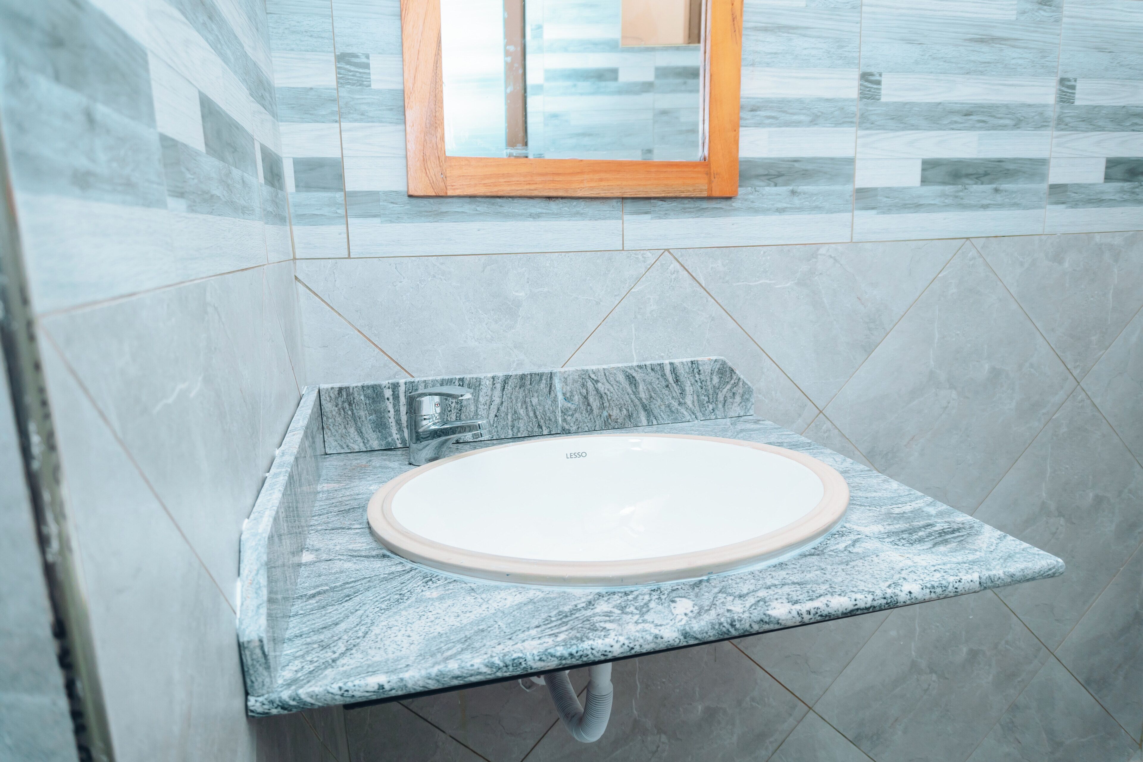 A bathroom with a marble sink, a mirror, and a tiled wall.