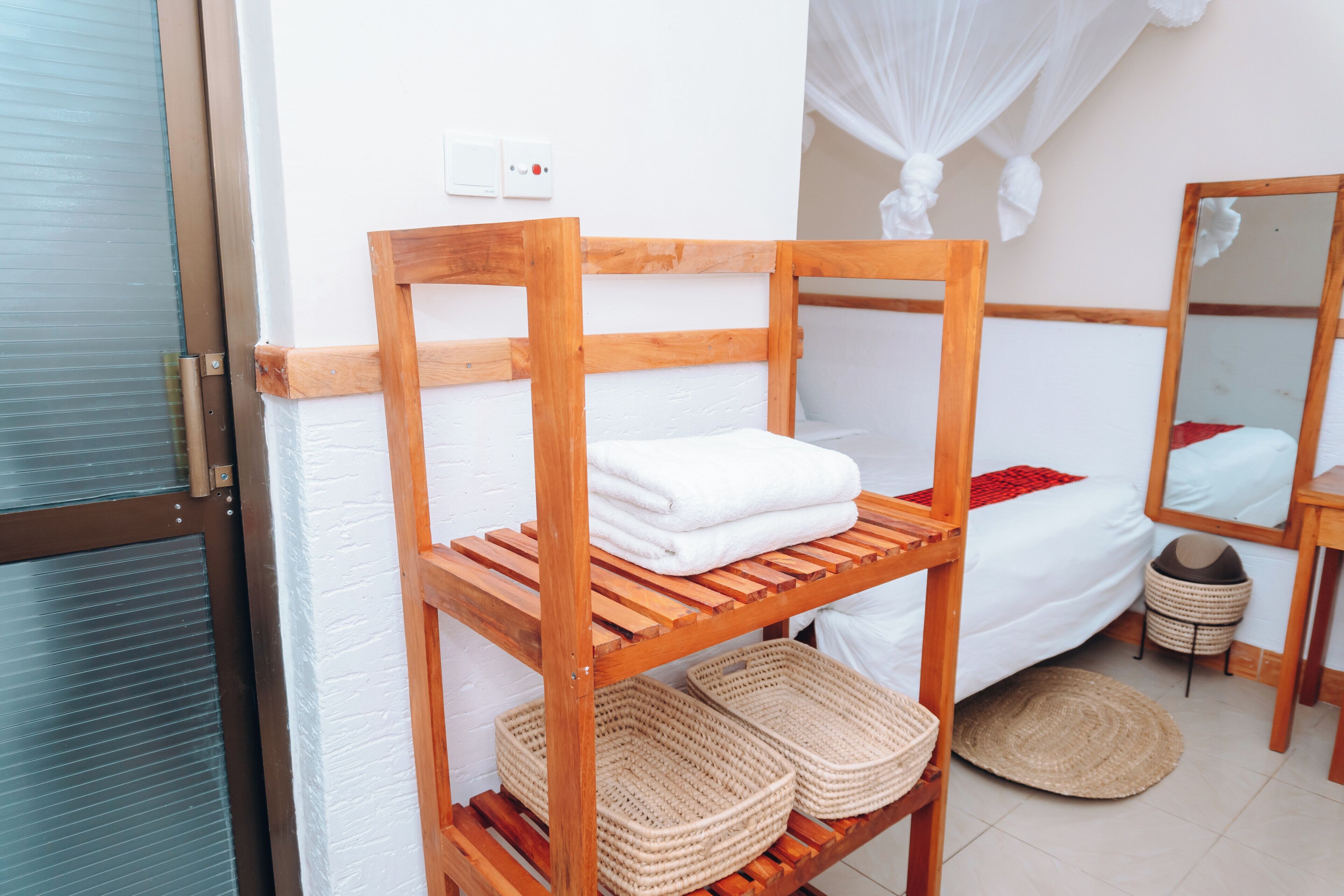 A wooden bunk bed with white bedding and a small shelf with woven baskets.