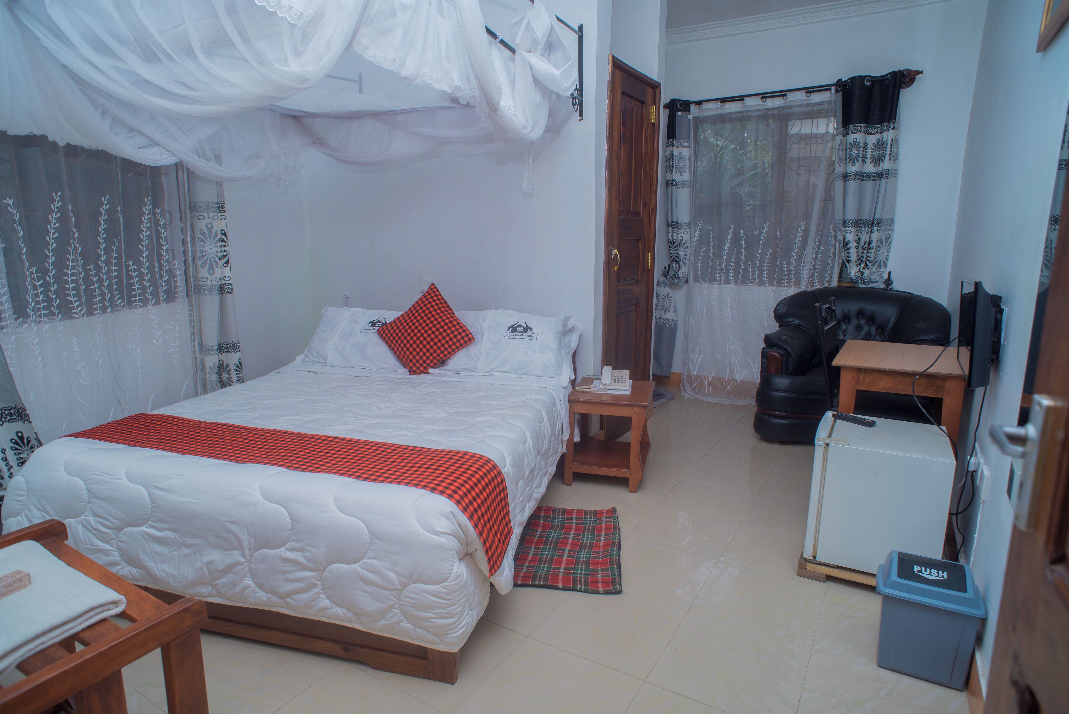 A bedroom with a bed, bedside table, chair, and a small desk with a computer.