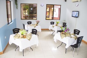 Enjoy meals in a beautifully set dining area with tables, chairs, and a flat-screen TV.